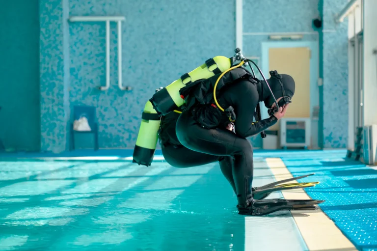 male-divers-in-scuba-gear-jump-into-the-pool-2024-12-02-02-01-10-utc