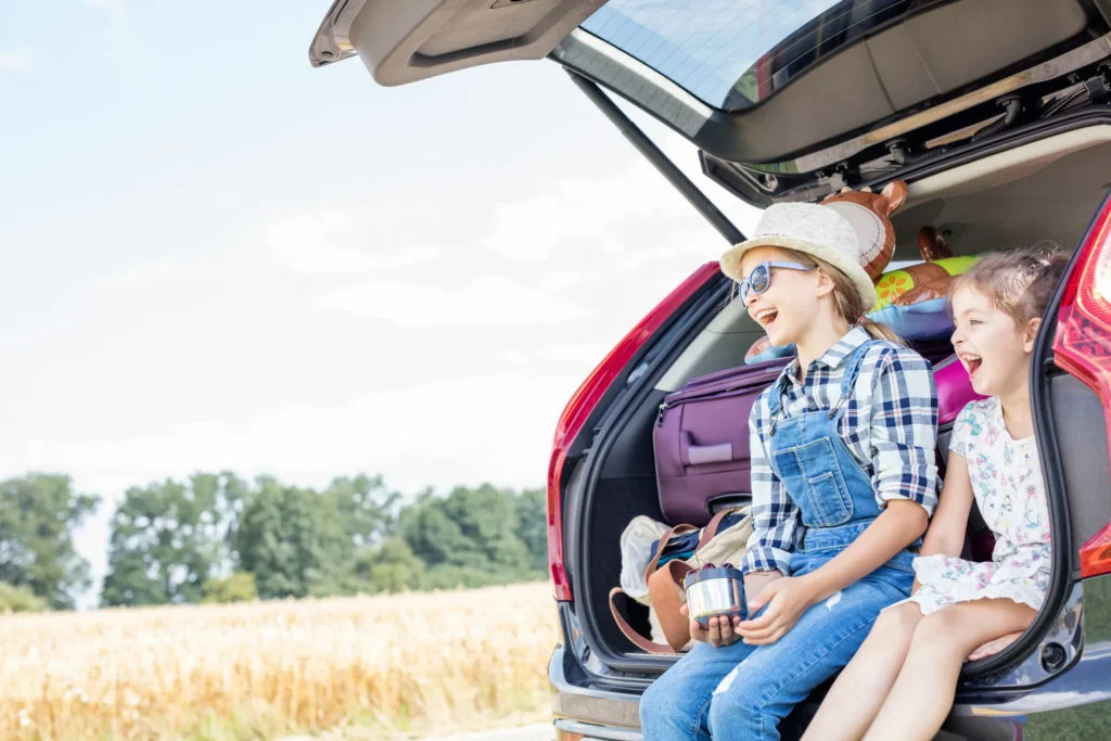smiling girls sit in car trunk on outing 2026 01 05 00 34 21 utc Alquiler de coches para familias en Mallorca
