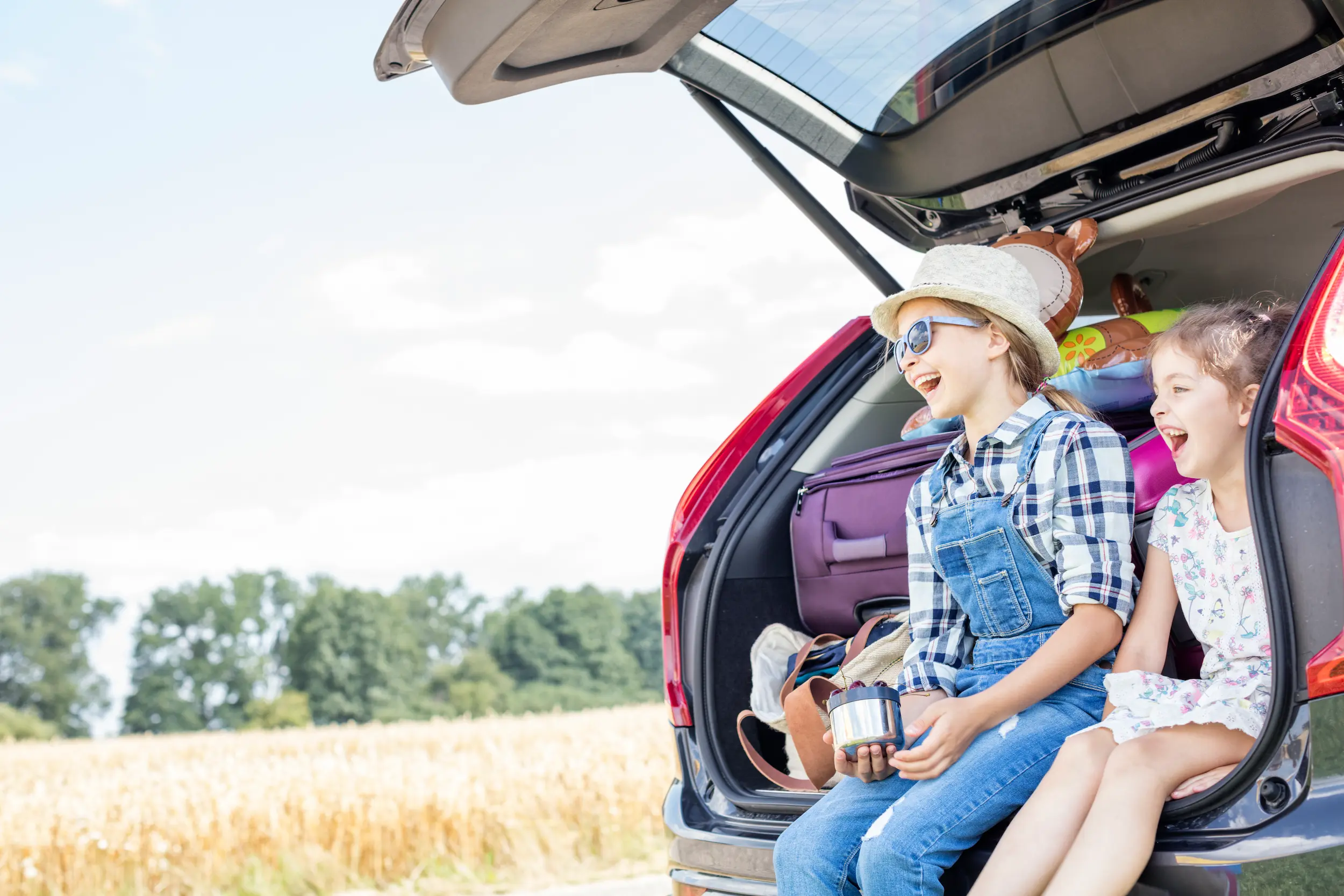 smiling girls sit in car trunk on outing 2026 01 05 00 34 21 utc Alquiler de coches para familias en Mallorca